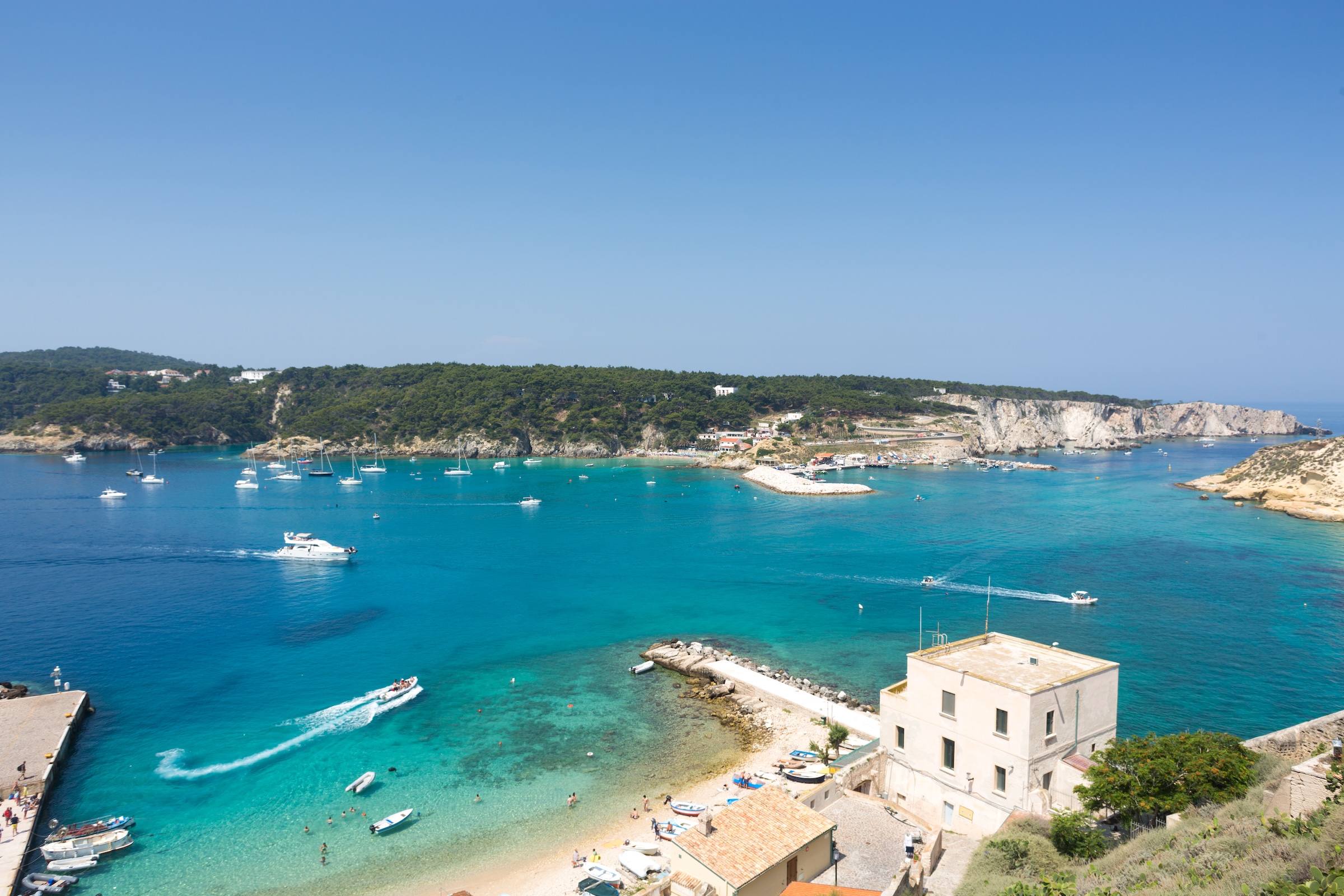 Baia turchese alle Isole Tremiti con barche e scogliere bianche